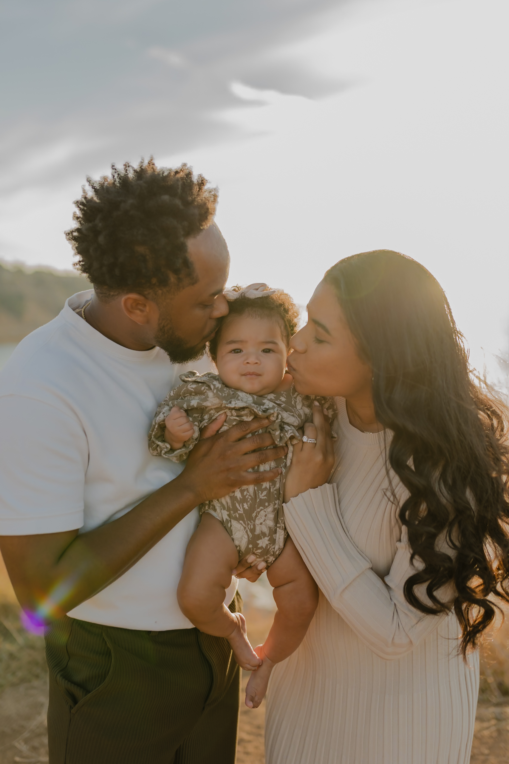 parents kissing infant on cheeks in palos verdes during sunset